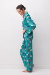Pijama de satén turquesa con estampado floral multicolor, compuesto por una camisa de manga larga con botones y cuello camisero, y pantalón largo a juego.
