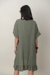 Vestido midi de lino color beige, con mangas cortas, cuello redondo, alforzas verticales en el pecho y detalle de volados en el ruedo.