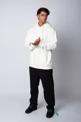 Buzo canguro oversize de tela friza, color negro, con capucha, cordones ajustables con logo y bolsillo frontal tipo canguro.