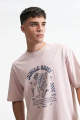 Remera color rosa claro de corte oversize con cuello redondo y mangas cortas. Estampado frontal con un tigre, estrellas y texto "Jungle Army".