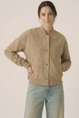 Campera tipo bomber cropped de gamuza sintética color beige, con cuello, puños y ruedo de rib elástico. Cuenta con bolsillos laterales ribeteados y cierre frontal con botones a presión metálicos.