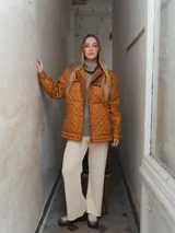 Campera acolchada color ladrillo con cuello marrón de pana, cierre frontal con botones a presión y bolsillos laterales.