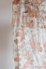 Pañuelo cuadrado de seda con estampado botánico en tonos beige y naranja. Bordes cosidos a mano.