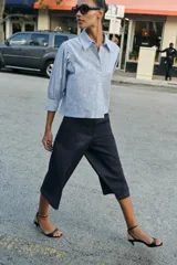 Camisa de cuello solapa y manga larga con puños abotonados. Presenta un diseño de rayas verticales azules y blancas con un estampado floral lineal superpuesto. Cierre frontal con botones.