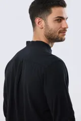 Camisa de lino y algodón color beige, de manga larga, con cuello mao y cierre frontal con botones. Presenta un pequeño bordado al tono en el pecho.