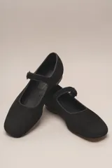Zapato plano estilo Mary Jane de cuero negro, con punta fina y tira ajustable con hebilla sobre el empeine.