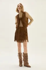 Falda corta de cuero color marrón, con diseño de flecos largos desmontables que cubren toda la prenda. Presenta un estilo western con cierre en la cintura.