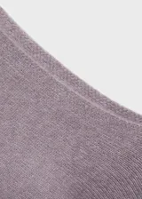 Jersey de punto asimétrico color malva, con diseño de hombro descubierto, manga larga y terminaciones en canalé.