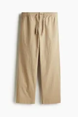 Pantalón de sirsaca de algodón color beige, con cintura elástica y cordón ajustable, cierre con botón, bolsillos laterales y bolsillos traseros insertados. Corte relajado.