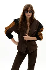 Chaqueta de gamuza con diseño de paneles en colores marrón, chocolate y negro. Presenta hombros estructurados, corte entallado en la cintura y botones forrados al tono.