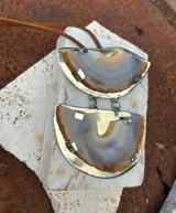 Collar de tiento de cuero con dije colgante compuesto por dos piezas de piedra ágata azul engarzadas en metal plateado.