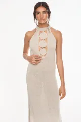 Vestido largo de tejido de punto color visón con escote halter y apliques circulares en relieve en el centro del pecho, de diseño recto y sin mangas.