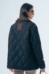 Campera acolchada de diseño matelasse con pespuntes ondulados, cuello clásico en contraste y cierre frontal con botones. Presenta bolsillos frontales con ribetes a tono y calce relajado.
