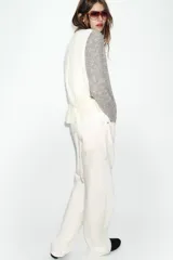 Chaqueta de punto de cuello redondo y manga larga, con diseño combinado que incluye una capa interior en tono crudo. Presenta cierre frontal con botones y puños acanalados.