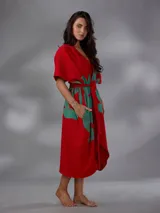 Capullo o kimono de paño 100% algodón, color rojo con estampado exclusivo en tono verde, de morfología amplia y envolvente, con bolsillos laterales y cinto independiente para ajustar la cintura.