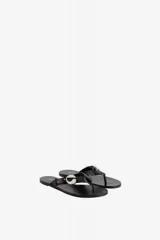 Sandalias de cuero vacuno color negro, tipo chinela, con tira de dedo y aplicación metálica con el logo de la marca en forma de 'C'.