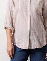 Camisa de lino marca Dash, color beige con rayas verticales blancas, cuello con solapa, cierre frontal de botones, bolsillo aplicado en el pecho y mangas largas con sistema para arremangar mediante presilla y botón.