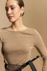 Top negro de manga larga acampanada con escote pronunciado en la espalda que se ajusta con lazos. La tela presenta una textura sutil con brillo, similar a un animal print discreto.