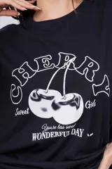 Remerón blanco de corte holgado con estampado de cerezas y texto en color rosa.