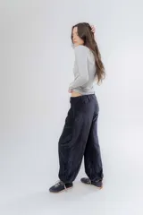 Pantalon de corte holgado y estilo bombacho, confeccionado en tela suave con ligero brillo. Presenta cintura elastizada en la parte trasera y puños elásticos en los tobillos que definen su silueta.