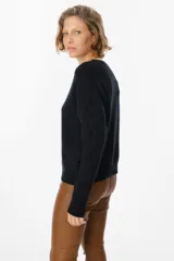 Sweater de punto negro con diseño de trenzas verticales en el frente y cuello redondo. Presenta un corte holgado con puños y ruedo acanalados.