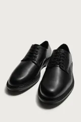 Zapato de vestir tipo derby, color marrón oscuro, con parte superior lisa, horma redonda, cordones y suela con ligero tacón.