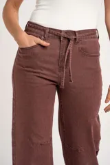 Jean de corte baggy y tiro alto, en color marrón desgastado, con diseño estilo barrel leg y lazo ajustable en la cintura.