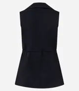 Chaleco negro de tejido punto, sin mangas, con cuello solapa y cierre frontal de dos botones dorados. El corte es acinturado y alargado.
