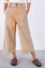 Pantalón capri color beige de pana con cintura alta, corte ancho y bolsillos laterales. Cierre con dos botones.