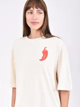 Remera negra de corte oversize con cuello redondo y manga corta. Presenta un pequeño estampado blanco en el pecho con un tenedor, un cuchillo y un emoji sonriente con texto.