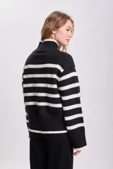 Buzo de punto con cuello alto, a rayas horizontales blancas y negras.