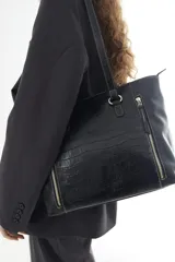 Cartera de cuero vacuno color marrón, de diseño amplio con paneles combinados de diferentes texturas y un panel central con relieve de cocodrilo. Cuenta con cierre frontal vertical y asas de hombro.
