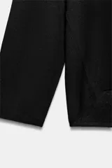 Jersey de punto fino negro con escote en V pronunciado, mangas largas y corte holgado con bajo asimétrico, más largo en la parte trasera.