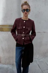 Blazer de cuello redondo y manga larga, confeccionado en tejido efecto ante. Presenta cierre frontal con botones, bolsillos con tapeta en el pecho y cinturón ajustable en la cintura.