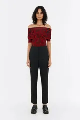 Pantalón negro de lana fría, corte ajustado, con cierre frontal de botón y cremallera, bolsillos laterales y cremallera invisible en el bajo de la pierna.