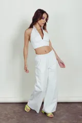 Pantalon de cuero blanco de corte holgado y tiro medio, con cintura elástica y diseño de paneles horizontales en las piernas.