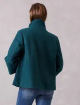 Tapado de tejido bouclé color marrón, con silueta evasé y largo a la cadera. Presenta cuello alto envolvente, cierre frontal oculto con botones a presión y bolsillos frontales de gran tamaño. Sus mangas son 3/4 con corte amplio y puños de tejido rib al tono que se extienden para cubrir las muñecas.