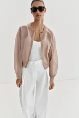 Chaqueta estilo bomber de punto color beige con acabado brillante, cuello redondo, manga larga con puños elásticos y cierre frontal con cremallera.