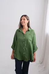 Camisa de lino de corte oversize, color verde seco, con cuello camisero, cierre frontal de botones de nácar, bolsillo frontal y mangas largas con sistema de ajuste.