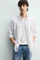 Camisa de corte regular fit en color azul, confeccionada en mezcla de lyocell y algodón, con cuello camisero, manga larga con puños abotonados, cierre frontal con botones y un bolsillo aplicado en el pecho.