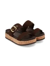 Sandalias de plataforma estilo flatform con dos tiras anchas en el empeine, confeccionadas en material marrón. La tira superior cuenta con una hebilla metálica grande en tono dorado y ojales decorativos. La plataforma posee una textura símil corcho.