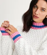 Suéter de punto blanco con cuello alto y puños acanalados con rayas horizontales rosas y azules.