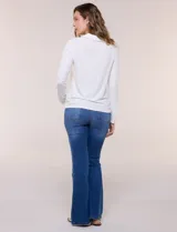 Remera de silueta al cuerpo de tejido de punto acanalado blanco, con cuello polo, abertura frontal con botones dorados y mangas largas con puños abotonados.