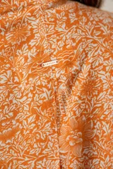 Kimono oversize color naranja con estampado floral blanco, mangas 3/4 y confeccionado en rayón.