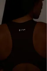 Top deportivo negro con diseño nadador, entrada para almohadillas removibles, bolsillo trasero y detalle reflectivo.