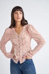 Blusa rosa con estampado de flores blancas y amarillas, cuello en V, manga larga abullonada y cierre frontal con botones.