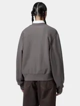 Buzo de cuello redondo color crema, de manga larga y calce relajado, con el logo de Carhartt bordado en el pecho.