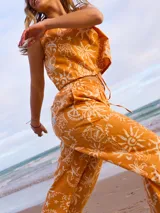 Pantalón largo de algodón color naranja quemado con estampado de motivos marinos en blanco (conchas, estrellas de mar, soles). Tiene cintura elástica y corte recto y holgado.