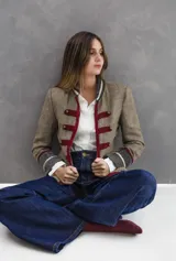 Chaqueta estilo napoleónico confeccionada en tejido tweed de lana con diseño de espiga. Presenta detalles en terciopelo de algodón en cuello y puños, decorada con cintas de pasamanería en color bordó y dorado, y botones metálicos empavonados.