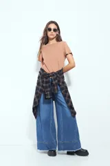 Remera de manga corta color marrón con escote a la base y calce relajado. Las mangas presentan terminación con ojales metálicos.